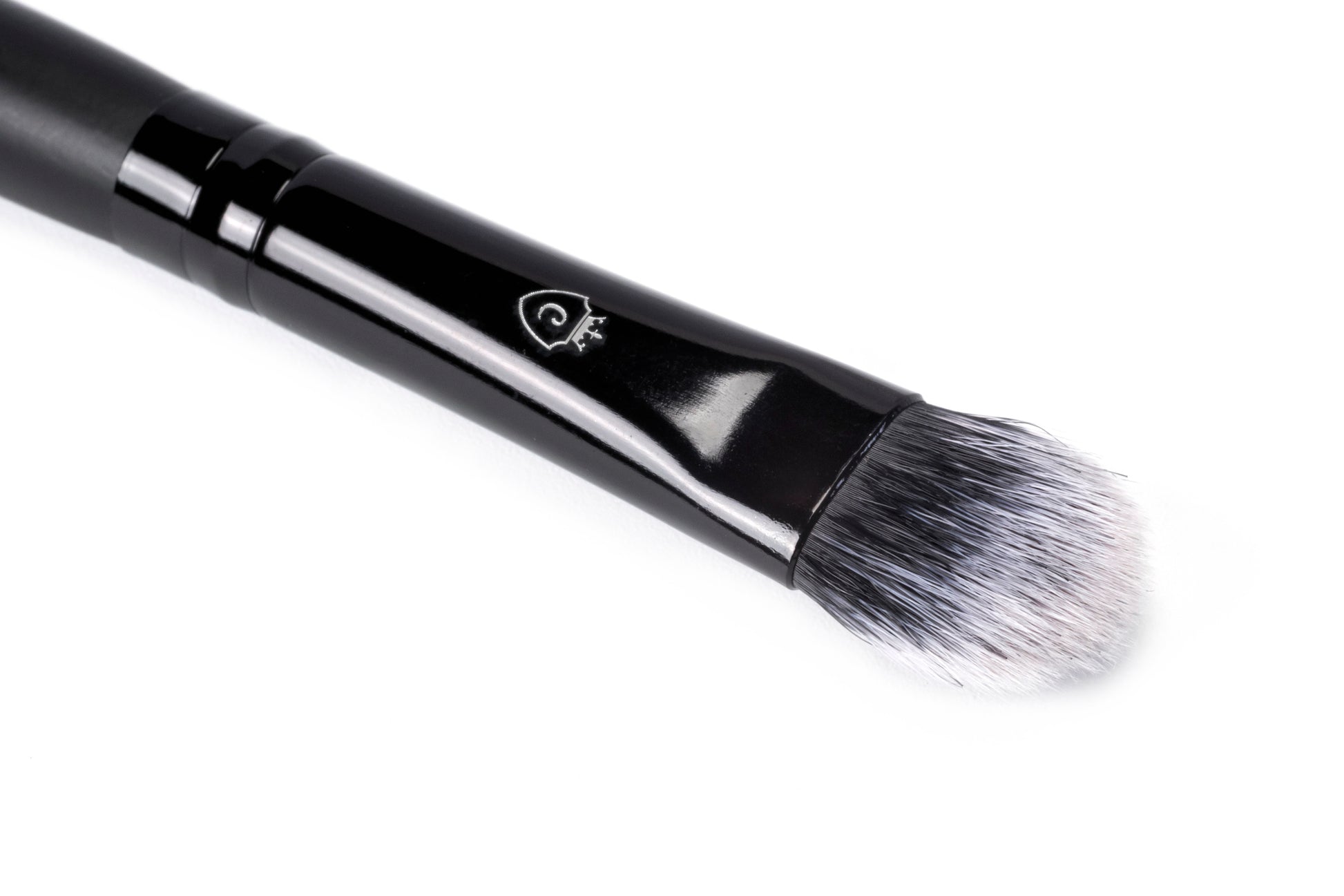 Close-up of a single makeup brush with a black handle, silver logo, and tapered black and white bristles.