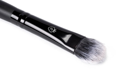Close-up of a single makeup brush with a black handle, silver logo, and tapered black and white bristles.