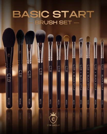Twelve black CTR makeup brushes with silver ferrules and various bristle shapes standing in a row on a reflective surface.